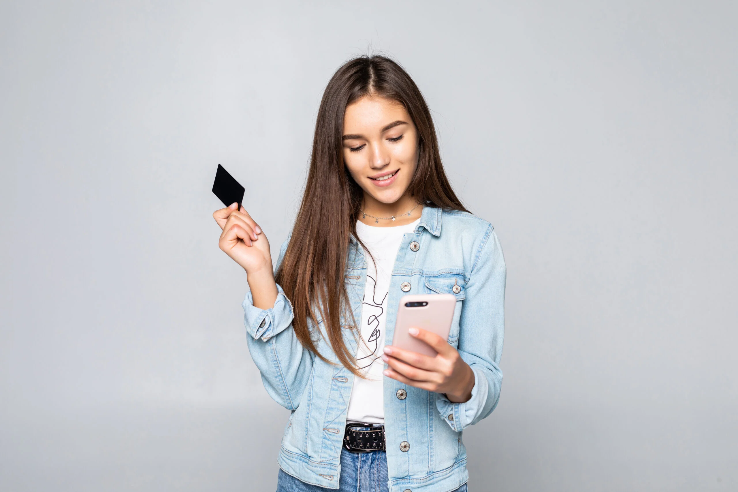 Portrait of a smiling young woman holding credit card isolated over white background