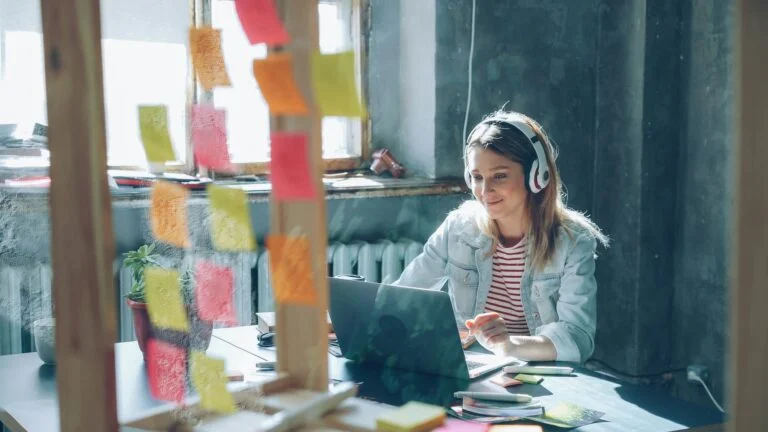 Imagem de mulher trabalhando em um notebook com fone de ouvido.